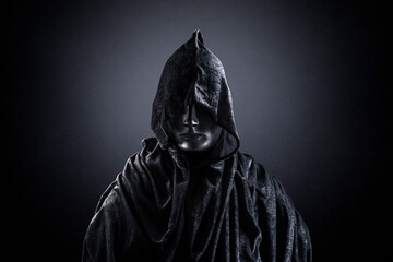 Scary figure with hooded cape in the dark