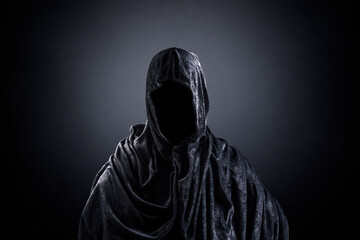 Scary figure with hooded cape in the dark - obrazy, fototapety, plakaty
