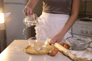 Obraz na płótnie Canvas Girl makes dough for dumplings in the kitchen