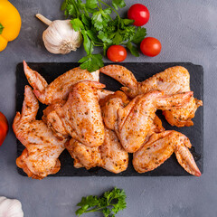 Raw marinated chicken wings with spices and vegetables. Top view, closeup