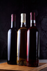 Fototapeta na wymiar Three bottles of wine without labels, red, white and pink on wooden boards