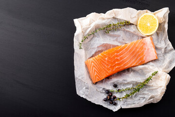 Raw salmon fillet  with lemon on a dark background. Text space, top view