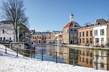 Schiedam, The Netherlands, February 11, 2021: view from the snow-covered quay towards the frozen river Schie on a cold but sunny day in winter