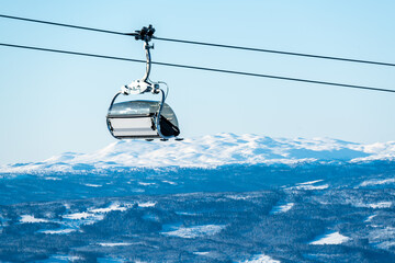 Empty ski lift on a cable with snow covered mountains in the background. Winter vactation.