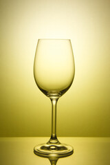 Empty wine glass for white wine on a yellow background.