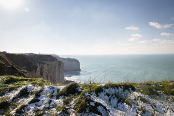 Vue sur les falaises d'Étretat enneigées au soleil, en hiver - Panorama grandiose des falaises normandes