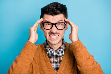 Photo of angry annoyed young guy hold fingers hands head wear glasses isolated on blue color...