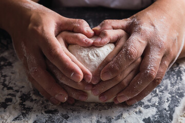Mom and daughter make a heart with their hands while preparing the dough.