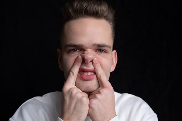 young guy, man, teenager grimaces, makes a nose like a pig