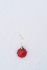 vertical view of red christmas ornament on the snow outdoors. Seasonal winter december concept. White snowy background with copyspace festive christmas.