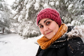 Horizontal portrait of young caucasian woman breathing fresh air outdoors under the snow. Environment and human contact with nature in winter under a snowstorm. Fresh air and nature concept.