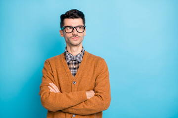 Photo of pensive minded young man look empty space crossed hands inspired idea isolated on blue...