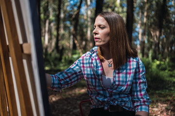 Fototapeta premium Young woman painting the landscape outdoors.