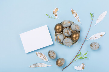 Easter Decoration with blue golden eggs, quail feathers, flowers on blue background. Happy Easter card concept.