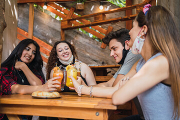 Cheerful friends toasting with a healthy orange juice in a bar.