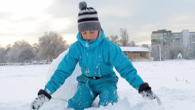 Boy playing in the snow throws a snowball at the camera