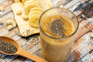 Banana smoothie with chia in a glass on a wooden table. Top view. Selective focus