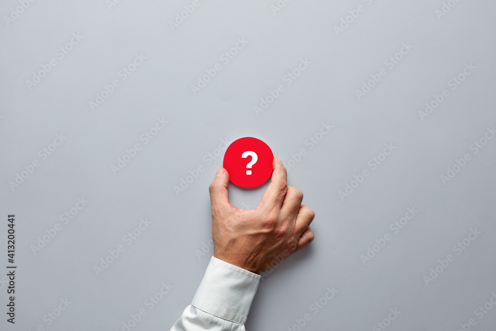 Poster businessman hand holding a red badge with question mark symbol. problem, uncertainty or solution in 