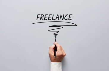 Businessman hand writing freelance on gray background. Freelance job or working as a freelancer