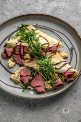 Pancakes with beef slices, Dorblu cheese, herbs and sauce. Delicious, hearty, nutritious breakfast. Balanced nutrition for beauty and health.