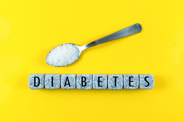 The word Diabetes is written on blocks and sugar on  on yellow background. Medical concept