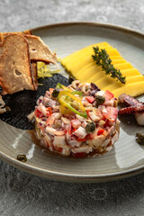 Octopus tartare with shrimps with fruit sauce and bruscheta chips in olive oil. Delicacy, luxury snack.