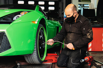 Mechanic changing the wheels of a high-end super sports car. Auto mechanic working in garage....