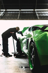 Mechanic changing the wheels of a high-end super sports car. Auto mechanic working in garage....