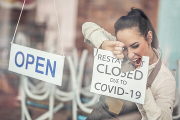 Happy employee reopens restaurant after covid-19 tearing a sign about closure, hanging sign saying...