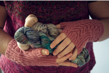 Woman hands with knitted mittens holding artisanal dyed yarn skein - Handcraft cozy warm lifestyle hobby
