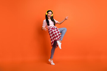 Full size profile photo of funny pretty person raise knee playing guitar isolated on orange color background