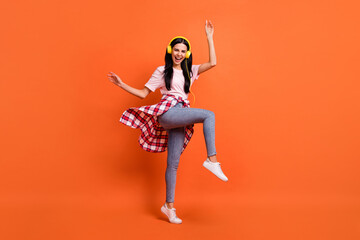 Full body profile portrait of excited pretty girl raise hands knee open mouth smile isolated on orange color background © deagreez