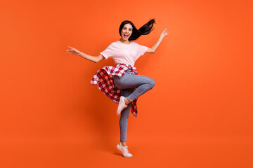 Fototapeta na wymiar Full size profile photo of optimistic nice brunette lady dance wear t-shirt jeans isolated on orange background