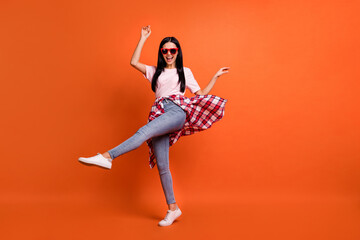 Fototapeta na wymiar Full size photo of optimistic nice brunette lady dance wear spectacles t-shirt jeans isolated on orange background