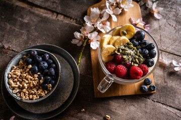 Yogurt with granola and fresh blueberries, in glass bowl over old wood background. Vintage effect.