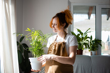 Beautiful young girl gardener is engaged in houseplants in the house. Home gardening, creating coziness and beauty, handwork, lifestyle.