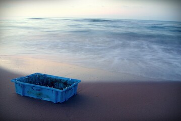 restos de basura traídos por el mar. Caja azul de plastico utilizada por los barcos pesqueros.