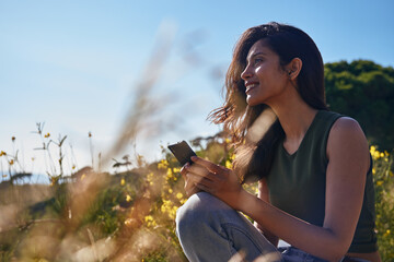 Contented lady sitting on a rock holding her phone