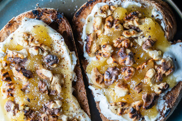 Two bread toast with cream cheese, roasted walnuts, honey, pepper and salt, close up, top view