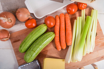 Ingredients for making baked zucchini rolls with vegetables and cheese on a wooden kitchen board