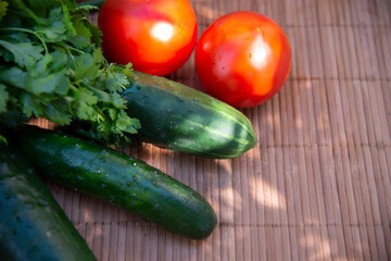 Red tomatoes , cucumbers and herbs on a bamboo napkin. Vegetable background. The concept of vegetarianism