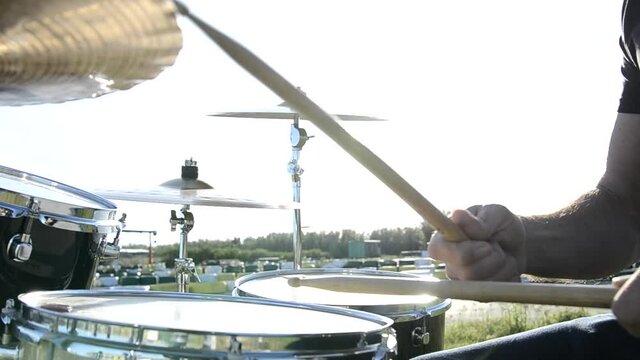 Musician playing drums A musician playing drums at an outdoor concert. The sun reflects off the plates of a battery. Detail shot of a musician playing the drums

