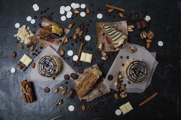 Lots of pastries and cakes, chocolate, frosting and cinnamon top view on a dark background, copy space
