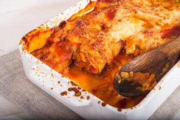 Zucchini rolls with vegetable filling baked with cheese in a baking dish close-up