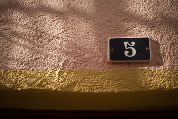 Numero 5 en la pared de una casa roza con amarillo