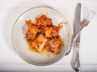 Zucchini rolls with vegetable filling baked with cheese in a plate on the kitchen table