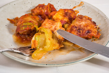 Zucchini rolls with vegetable filling baked with cheese in a plate on the kitchen table close-up