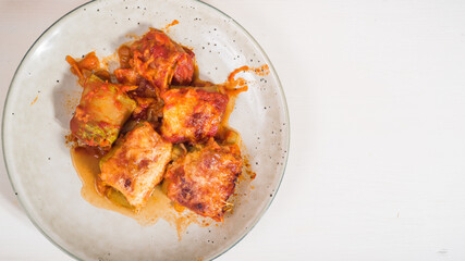 Zucchini rolls with vegetable filling baked with cheese in a plate on the kitchen table, copy space