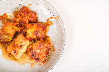 Zucchini rolls with vegetable filling baked with cheese in a plate on the kitchen table, copy space