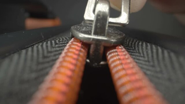 A closer look of the zipper closing the luggage bag using the hands